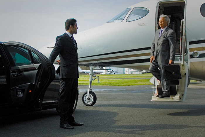 A luxurious black limousine parked outside an airport terminal, ready to provide premium transportation service.